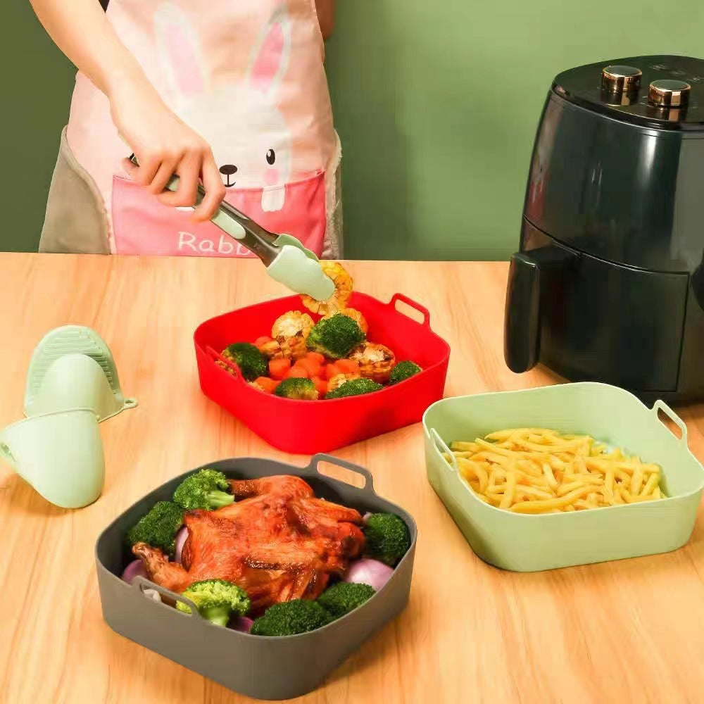 Air fryer basket liner lifting a batch of food out by the two handle tabs