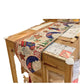 Table runner with stocking and moon pattern over a wooden table edge with a red tassel, not an option design
