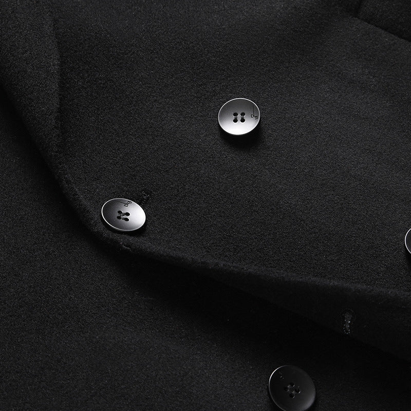 Close-up of the black wool coat showing the front edge and two dark four-hole buttons on the thick cloth