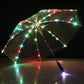 Clear LED umbrella with multicolor LED dots along the ribs, tilted at night with the handle tip lit