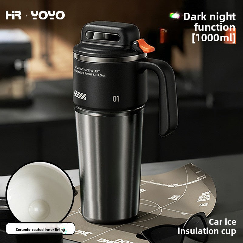 Black 1000ml insulated stainless steel travel mug with flip lid latch on a dark kitchen counter