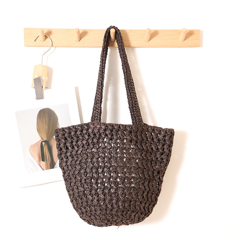 Coffee paper straw shoulder bag with open crochet weave hanging on a wooden wall rack