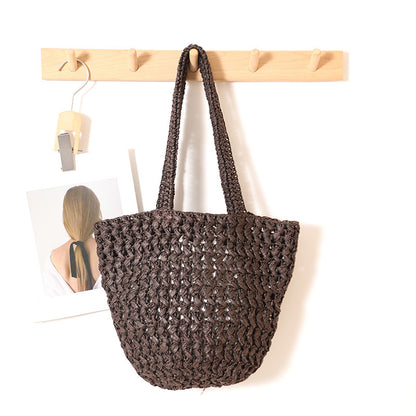 Coffee paper straw shoulder bag with open crochet weave hanging on a wooden wall rack