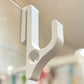 White resin single hook with a round hole over the top edge of a glass shower door