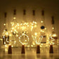 LED wine bottle stopper light string glowing warm white inside a clear glass bottle on a table