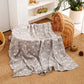 Large cotton muslin gauze baby blanket laid out, showing the loose breathable weave and print