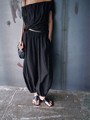 Black balloon leg pants with an elastic gathered waist and gathered ankle cuffs