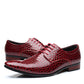 Pair of wine red crocodile embossed pointed toe derby dress shoes with a red brown heel, side view on white