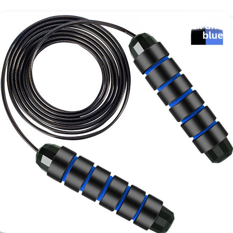 Black and blue skipping rope laid flat on white with the coated steel cable coiled