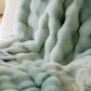 Corner of a ruched plush throw blanket showing the rows of soft fabric bubbles