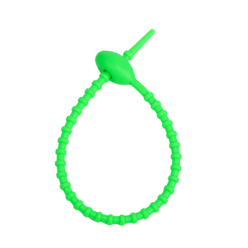 Soft silicone tadpole cable tie coiled into a loop to show the reusable cinch closure