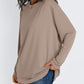 Khaki loose long sleeve rayon top with dropped shoulders worn with denim shorts, three quarter view