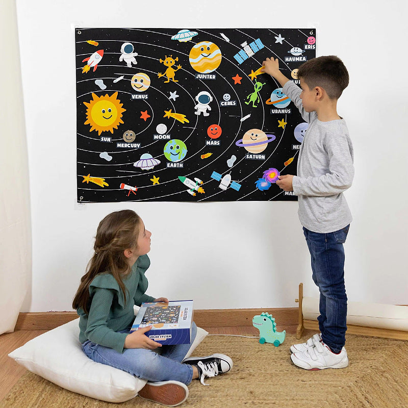 Two children playing with a space and solar system hanging felt story board on the wall