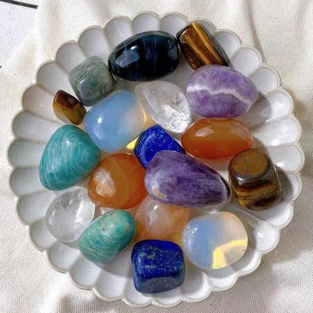 Natural polished tumbled stones arranged in a white scalloped dish