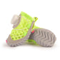 Small dog walking outdoors in black soft sole shoes on a gravel path