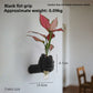Metallic hand shaped wall vase gripping a clear glass tube with foliage, side view