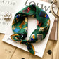 Green equestrian scene printed square scarf with a satin sheen and hemmed edges, shown displayed