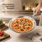 Hand holding a hammered flat pan carrying a baked pizza with tomatoes, olives and arugula