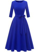 Blue vintage swing dress with round neck, bow belt and full pleated skirt, front view