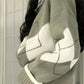 Cream and matcha green argyle sweater seen from the side, diamond panels across the chest and sleeve