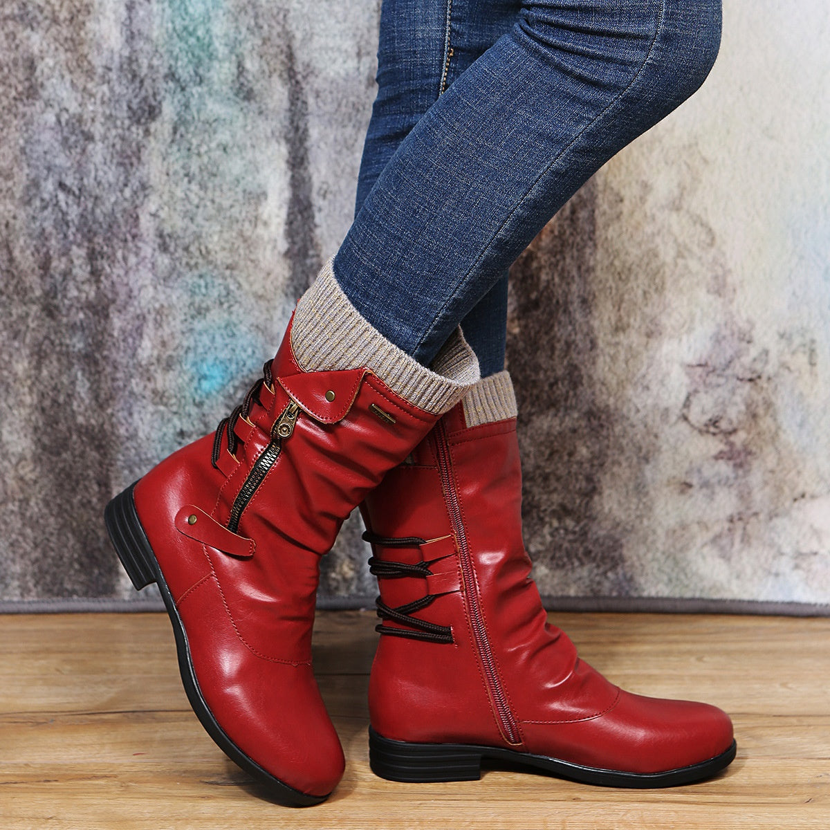 Red glossy mid calf slouch boots with a knit cuff, a diagonal zipper and back cords, worn with blue jeans