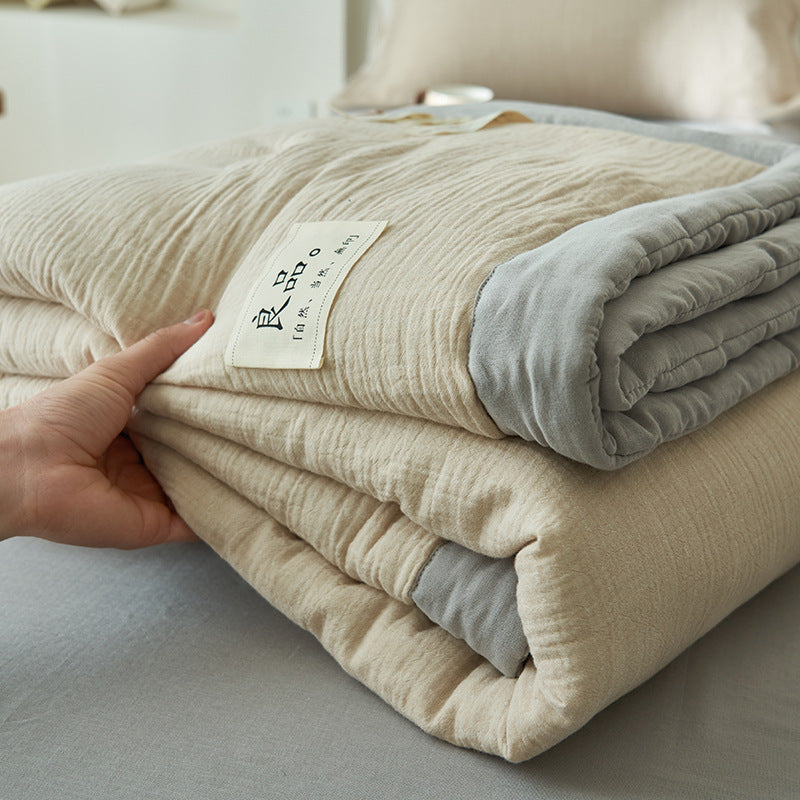 Lightweight gauze summer quilt spread across a bed in a bright bedroom