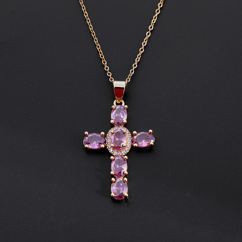 Cross pendant set with red cubic zirconia stones, close up on the paved arms