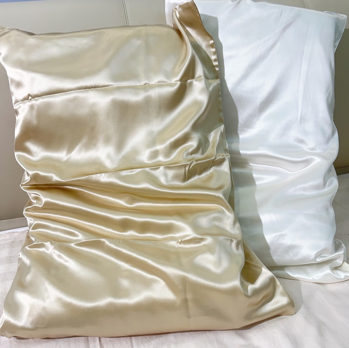 Champagne gold mulberry silk pillowcase beside a white pillowcase on a sofa