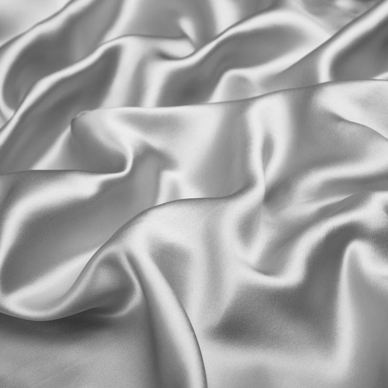 Mulberry silk pillowcase folded into fluid drapes on a white sheet