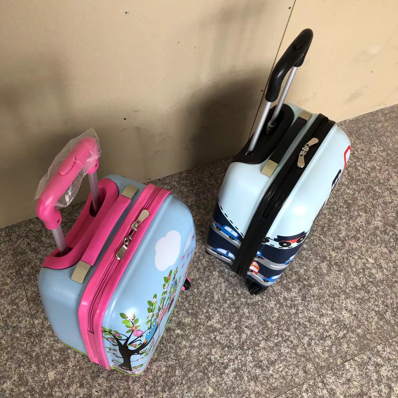Two children's ABS trolley cases with cartoon prints and telescopic pull handles upright