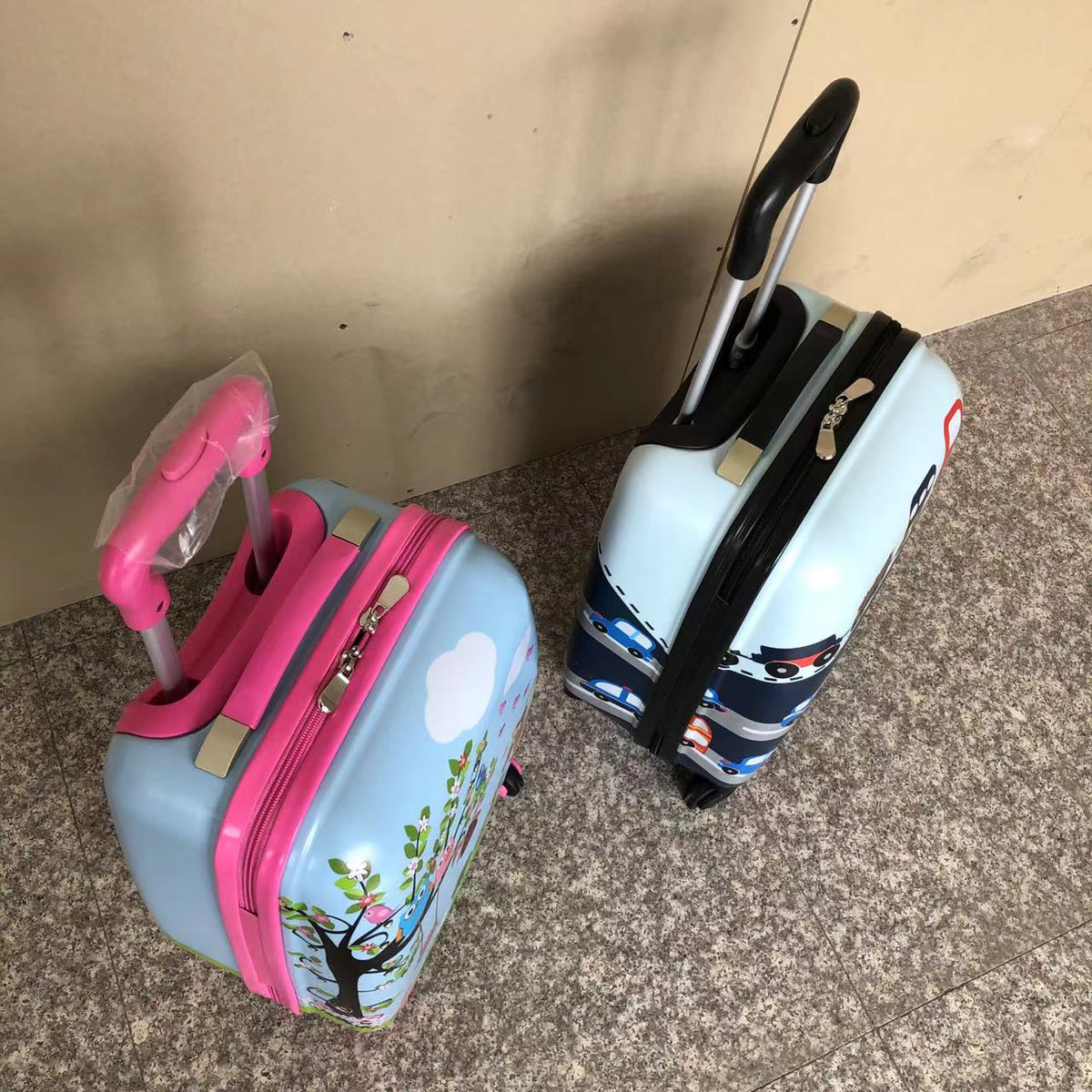 Two children's ABS trolley cases with cartoon prints and telescopic pull handles upright