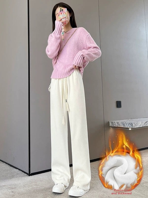 Woman in cream wide-leg drawstring pants and a pink sweater taking a mirror photo, fleece lining icon at lower right