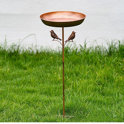 Styled metal bird bath set on a garden border ready for small birds
