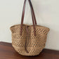 Side profile of the woven straw tote showing its roomy depth and natural khaki straw weave