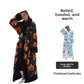 Woman in a long black pumpkin print fleece bathrobe with black plush notched collar, cuffs and hem