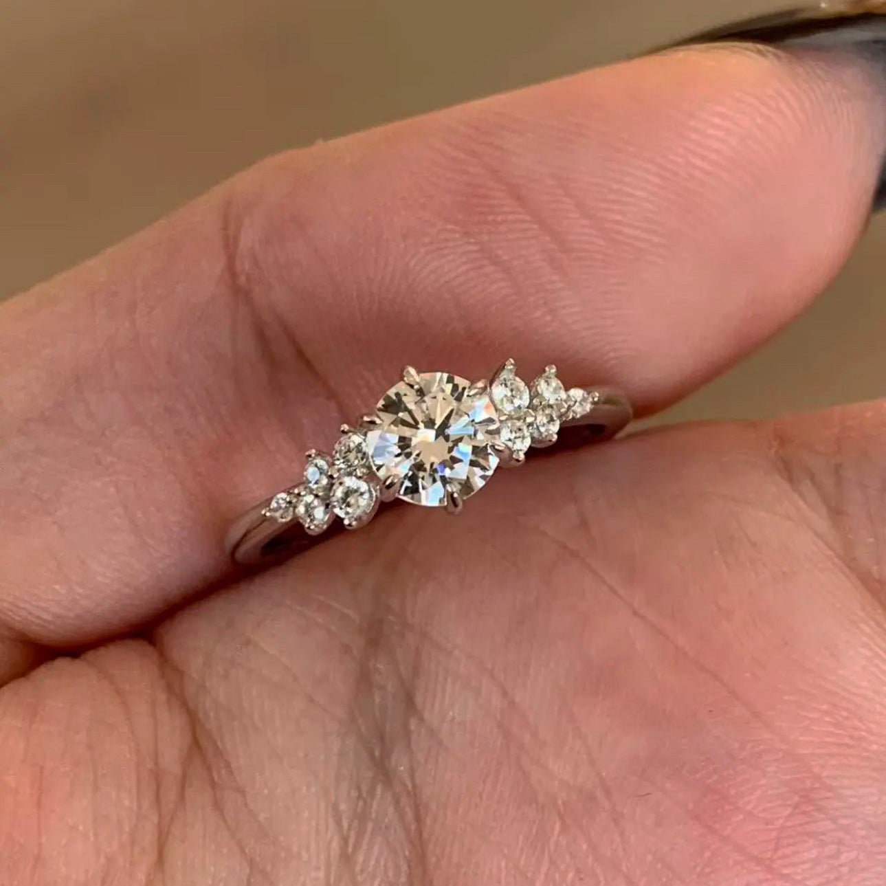 Close view of the sterling silver ring, faceted round cubic zirconia center with scattered accent stones on the shoulders