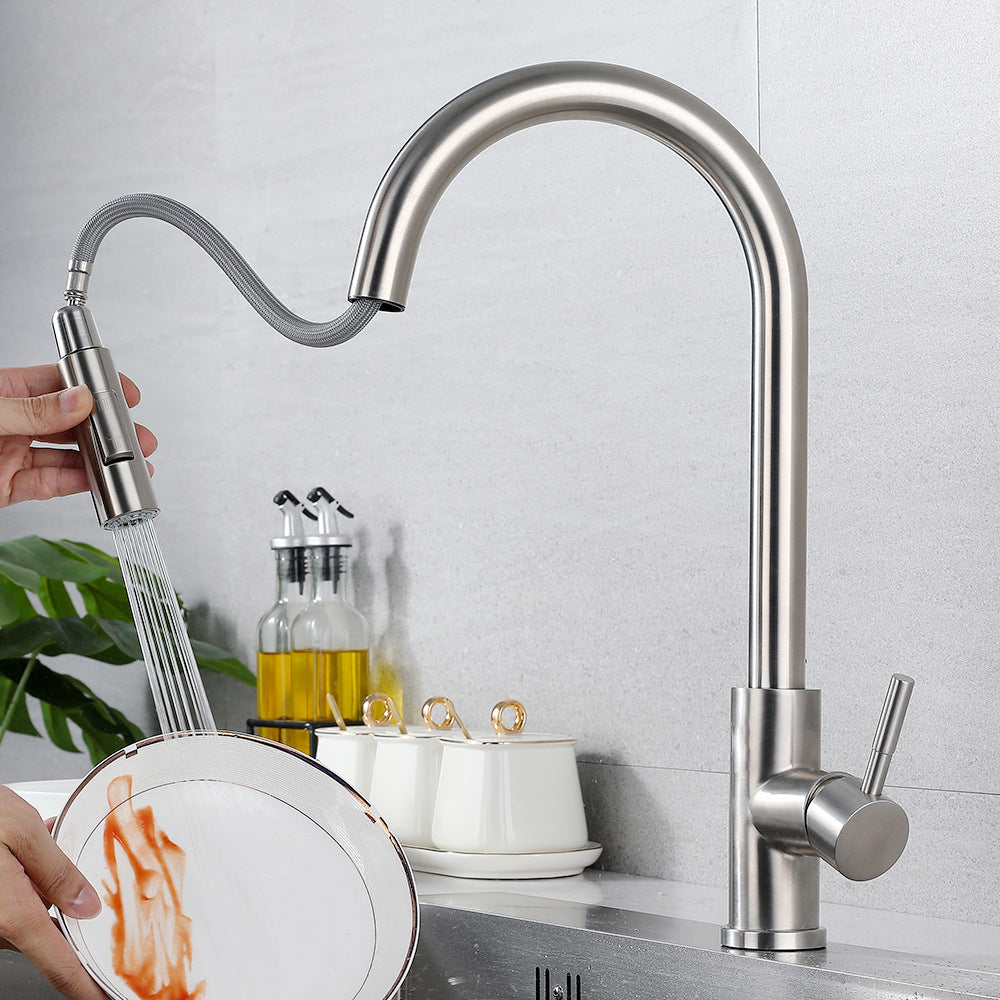 Brushed steel pull out mixer in use, spray head held in one hand rinsing a plate over the sink