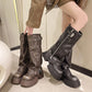 Model pulling on dark brown chunky platform boots with side zipper and buckle strap beside a black pair