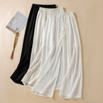 Linen blend wide leg trousers in white and black laid flat with drawstring waist
