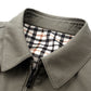Close view of the turn-down collar and zipper of a khaki cotton jacket with a black and white plaid lining
