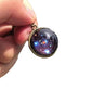 Glass solar system ball pendant in a bronze tone ring held against a plain white background