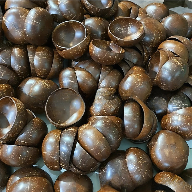 Pile of raw coconut shell halves with dark glossy outer surfaces