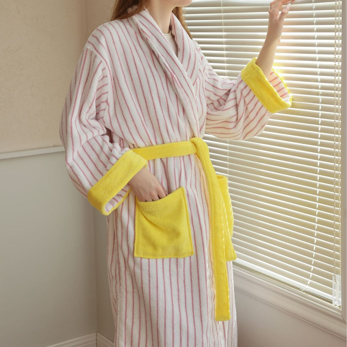 Side view of a pink and white striped cotton terry bathrobe with yellow trim and patch pocket