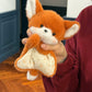 Orange plush fox squishy bean bag toy held up, pointed ears and yellow floral cotton apron