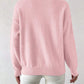 Back view of a pink loose pullover sweater with ribbed hem and cuffs worn with white trousers
