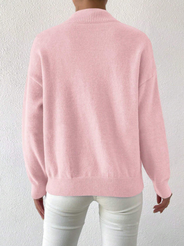 Back view of a pink loose pullover sweater with ribbed hem and cuffs worn with white trousers