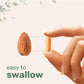 Orange turmeric capsule held by fingers next to an almond for size comparison