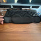 Black 3D contoured sleep eye mask with eye hollows held up in front of a desk keyboard, Eye Mask 3D option
