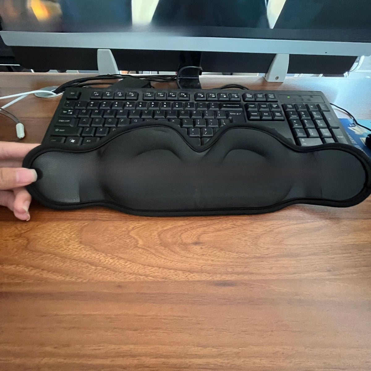 Black 3D contoured sleep eye mask with eye hollows held up in front of a desk keyboard, Eye Mask 3D option