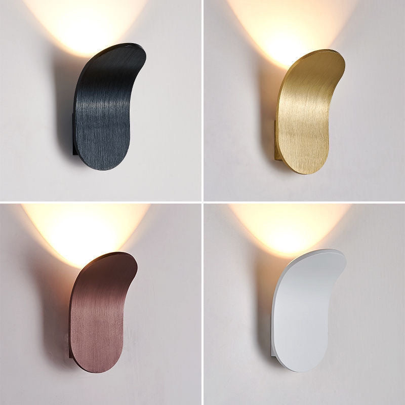 Four curved wall lamps in black, gold, copper brown and white, each with a glow rising up the wall